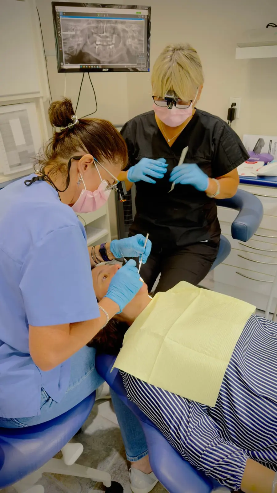 Two dental professionals caring for a patient at Gateway Dental Clinic